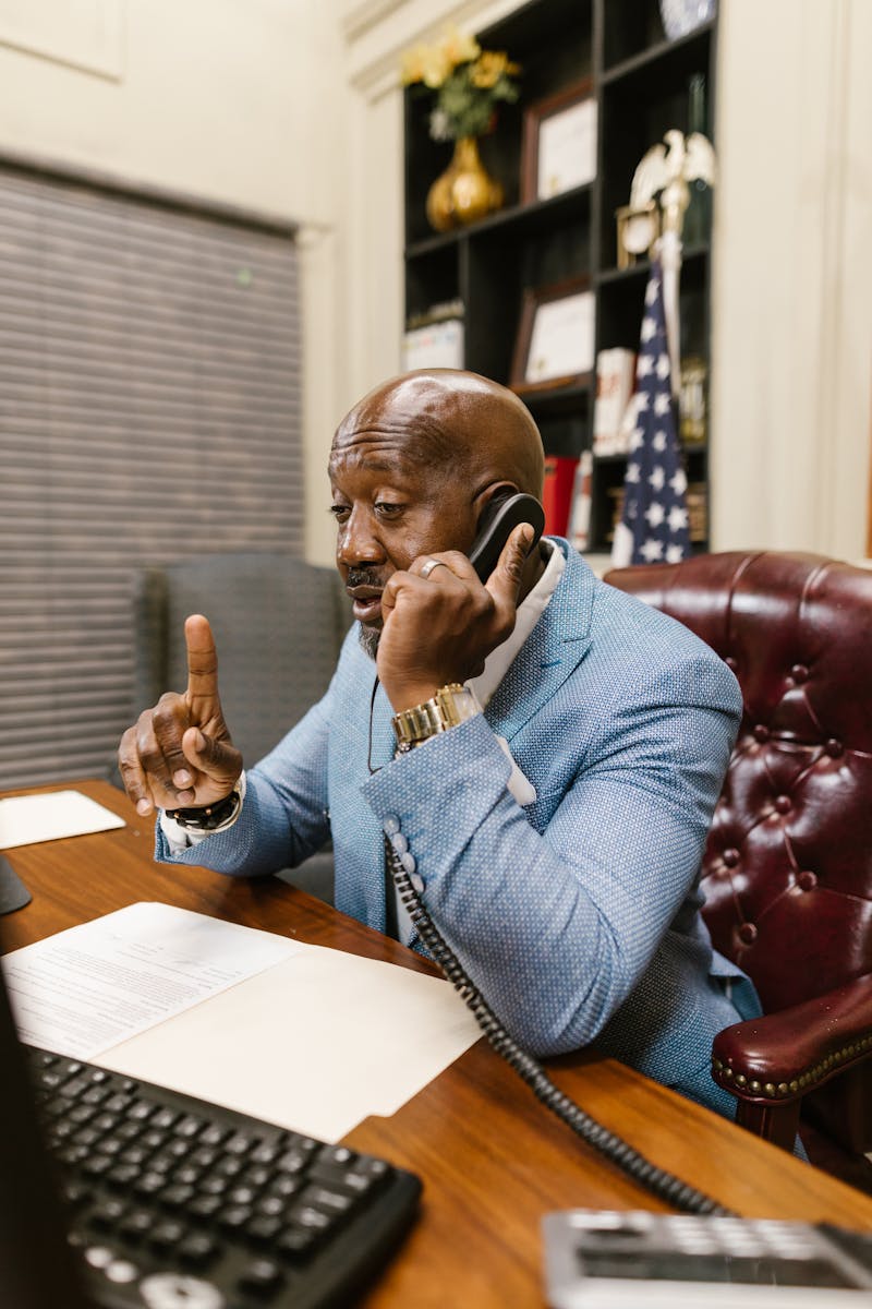 Businessman in a suit making a phone call and taking notes in a professional office setting.